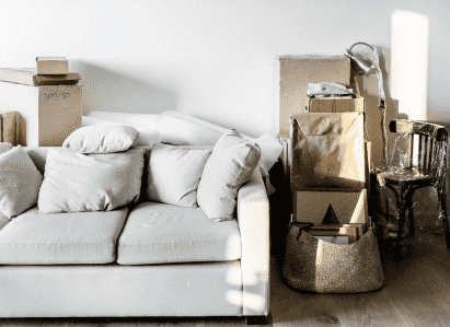 white fabric sofa surrounded by clutter and cardboard storage boxes