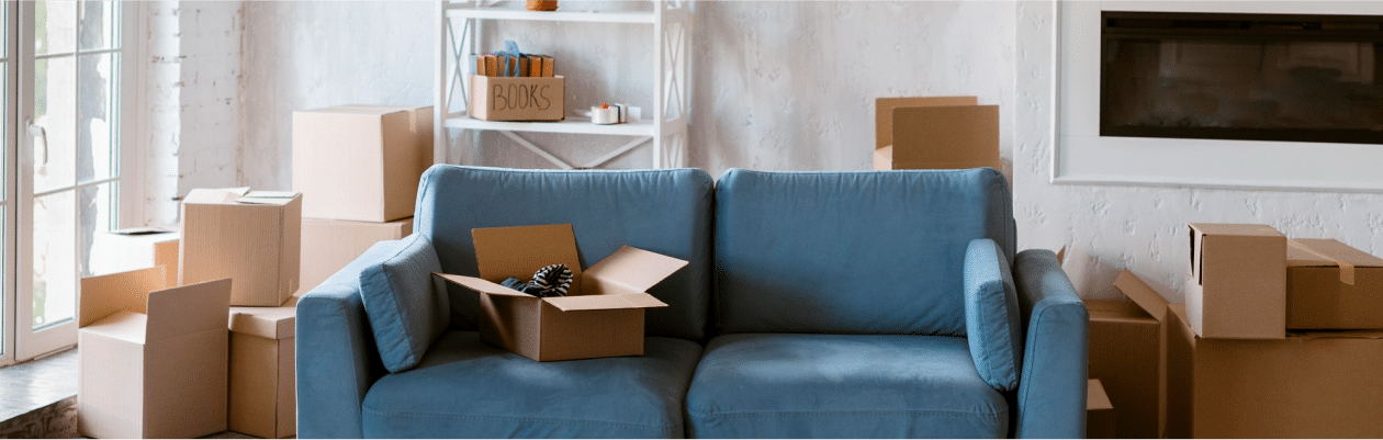 blue fabric sofa surrounded by cardboard boxes that need unpacking