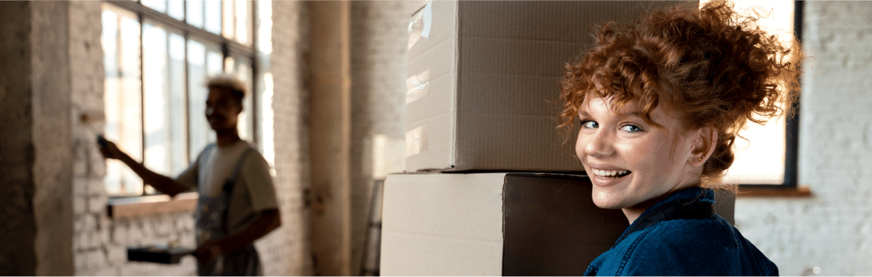 young woman moving cardboard boxes into her home